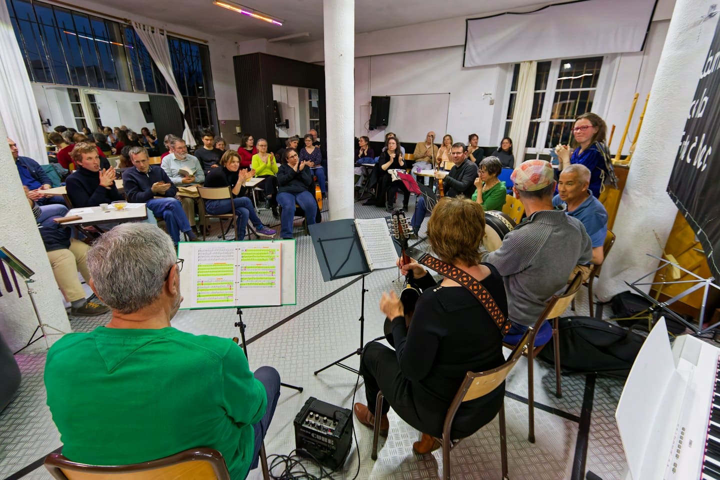 People play musical instruments while an audience claps along.